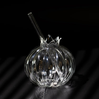 A clear ribbed glass bowl with a matching glass straw, photographed on a dark reflective surface against a black background.